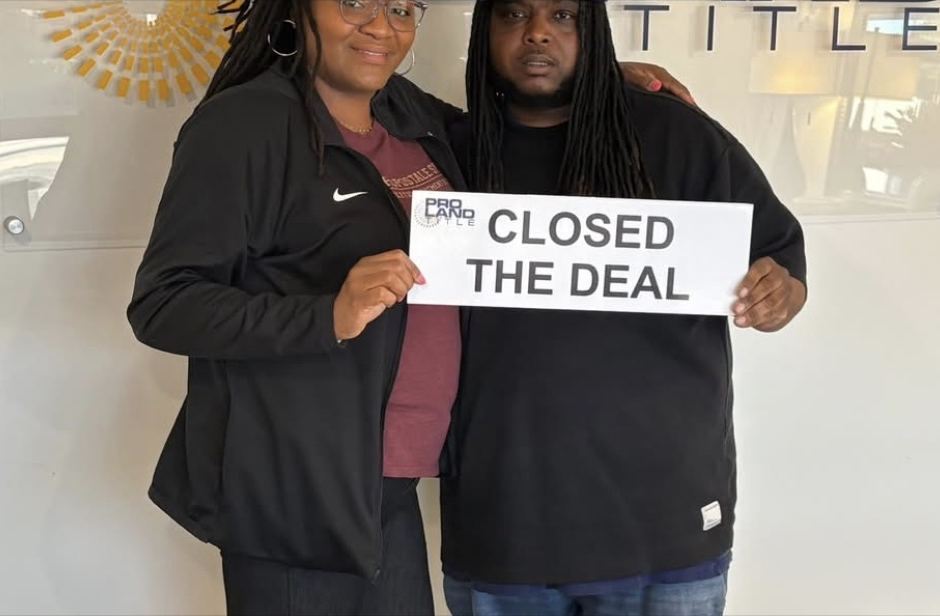 Clients holding a Closed the Deal sign at their home closing
